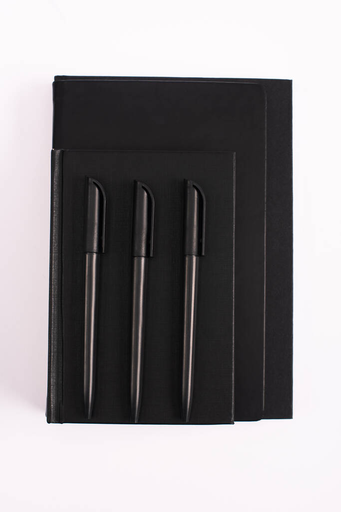 Siyah fotokopi kitaplarındaki kalemlerin beyaza izole edilmiş üst görünümü  - Fotoğraf, Görsel