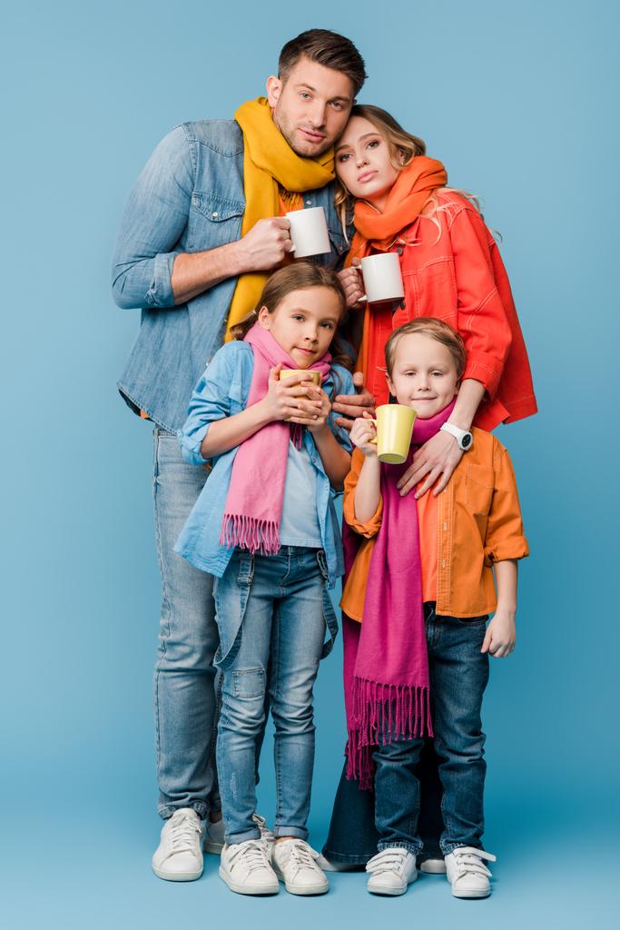 ziek familie met kinderen houden kopjes met warme dranken op blauw - Foto, afbeelding