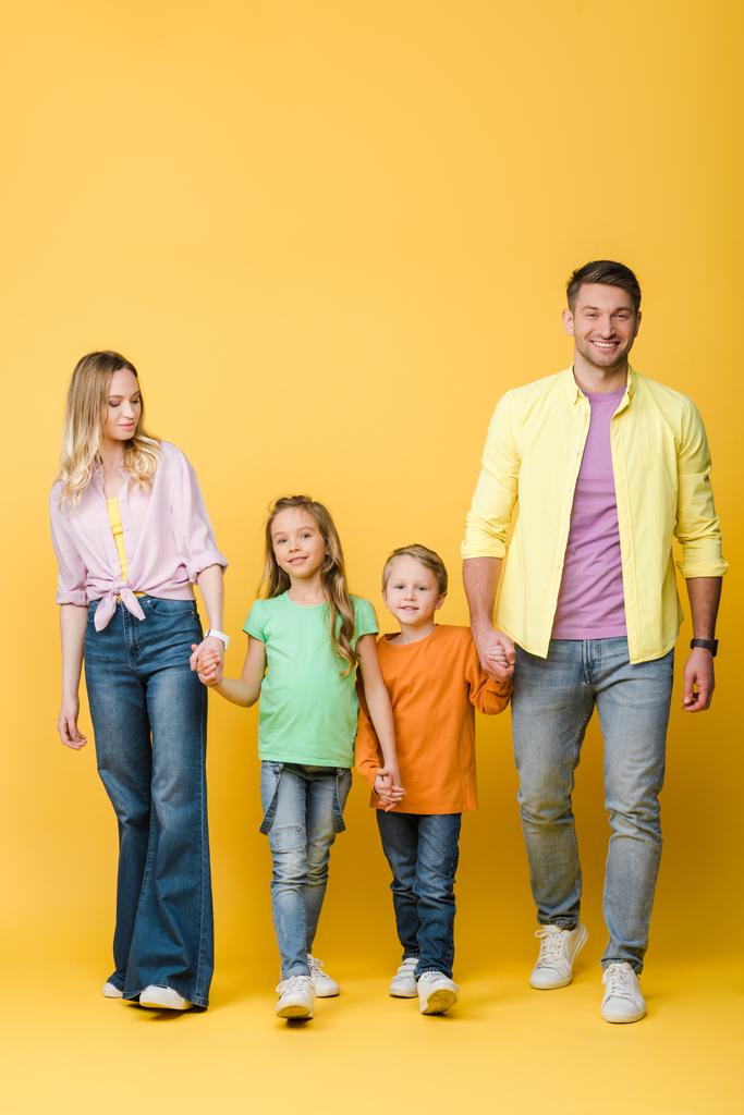 happy parents holding hands with kids on yellow - Photo, Image