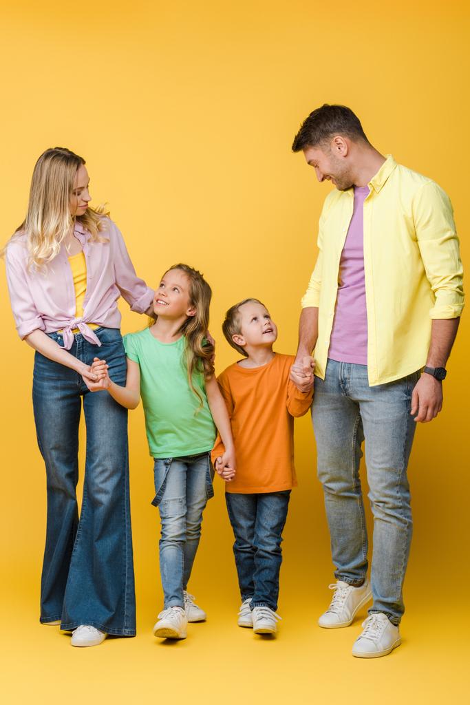 счастливая семья, держащая за руки детей на желтом
 - Фото, изображение
