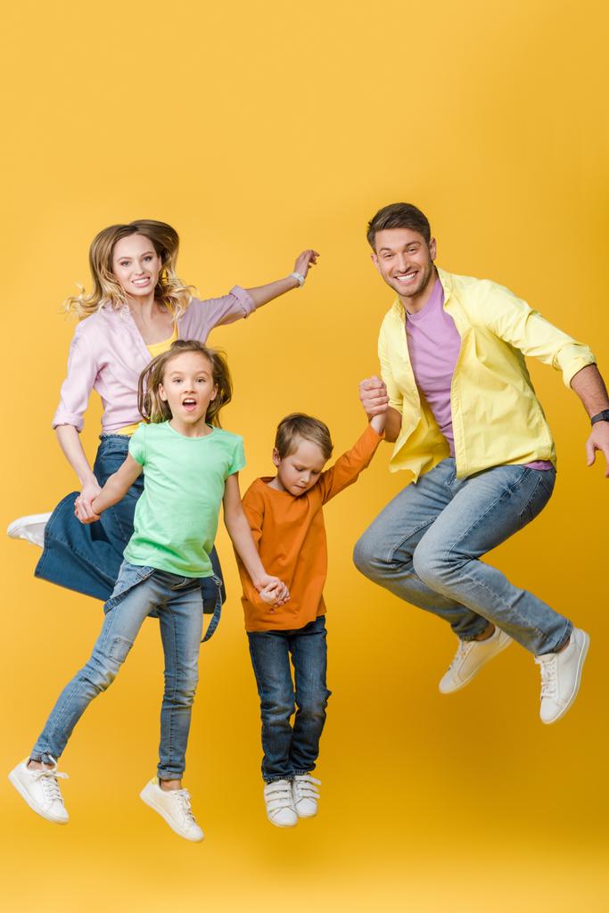 podekscytowany skoki rodzinne i trzymanie się za ręce na żółty - Zdjęcie, obraz