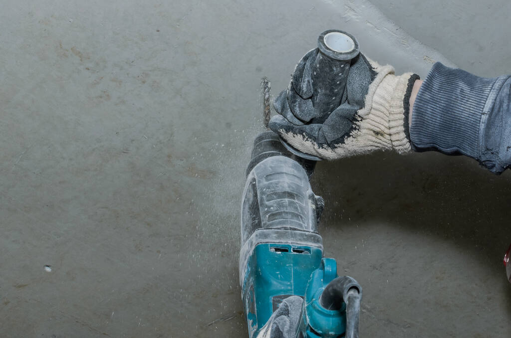 Trabalhador broca uma parede de concreto com uma broca de martelo
 - Foto, Imagem