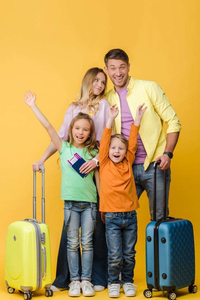 χαρούμενη οικογένεια ταξιδιωτών με αποσκευές, διαβατήρια και εισιτήρια σε κίτρινο - Φωτογραφία, εικόνα