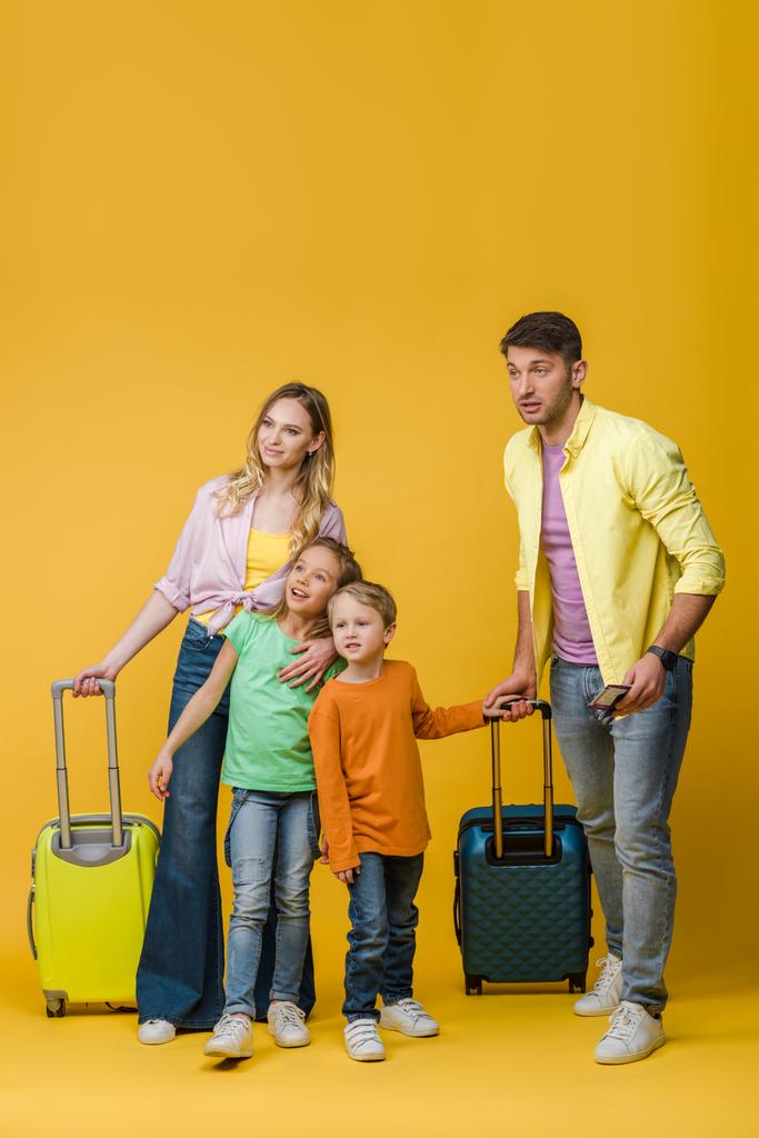 padres felices y niños con bolsas de viaje, pasaportes y billetes en amarillo
 - Foto, imagen