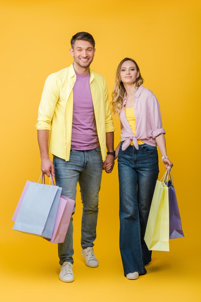 黄色の買い物袋を持っている陽気なカップル - 写真・画像