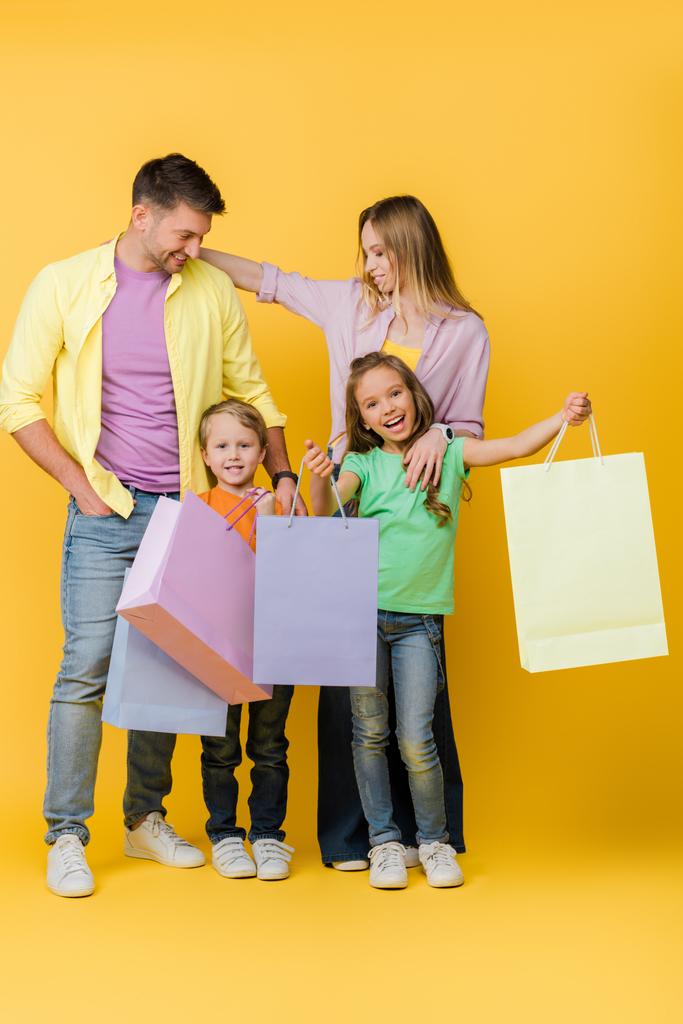 幸せな両親と黄色のショッピングバッグを持つ子供たち  - 写真・画像