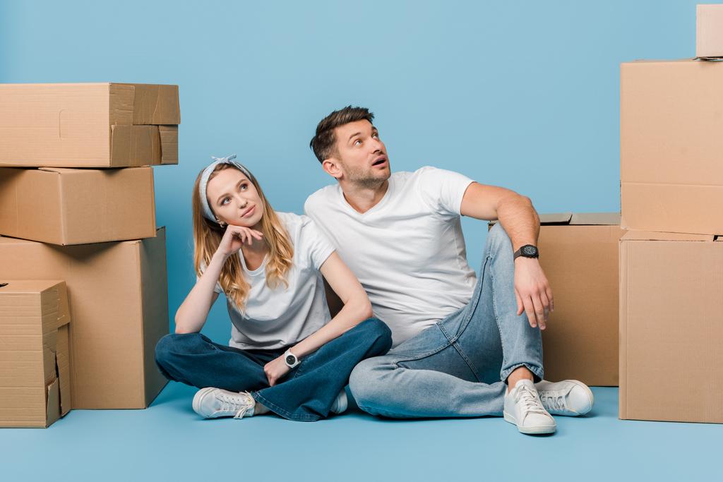 мечтательная пара, сидящая с картонными коробками для перемещения на синий
 - Фото, изображение