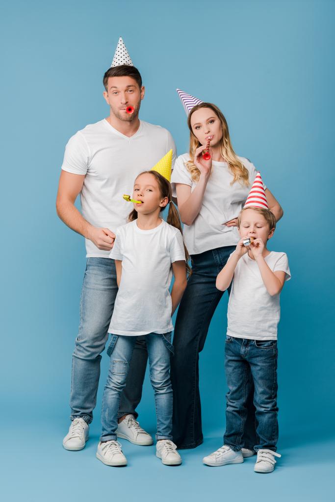 Ευτυχισμένη οικογένεια σε καπάκια πάρτι γενεθλίων με φυσητήρες στο μπλε - Φωτογραφία, εικόνα