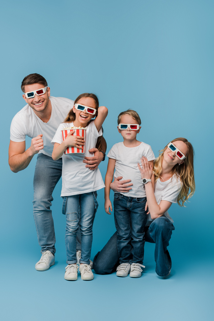 allegra famiglia guardando film in bicchieri 3d e tenendo secchio popcorn su blu
 - Foto, immagini