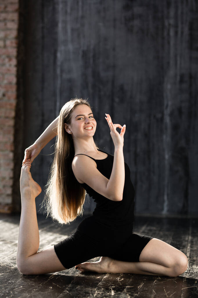 Молода дівчина в чорному спортивному одязі робить йогу і показує знак добре, тому що йога не складна
 - Фото, зображення