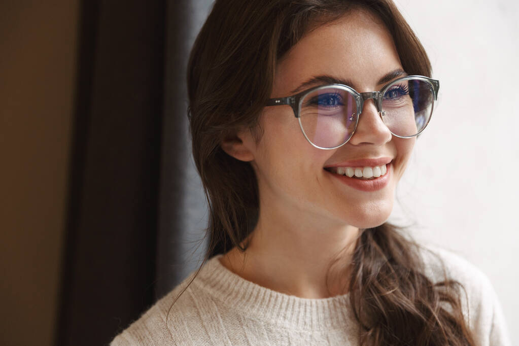 Imagem de jovem bela mulher caucasiana vestindo óculos sorrindo enquanto descansa no café
 - Foto, Imagem