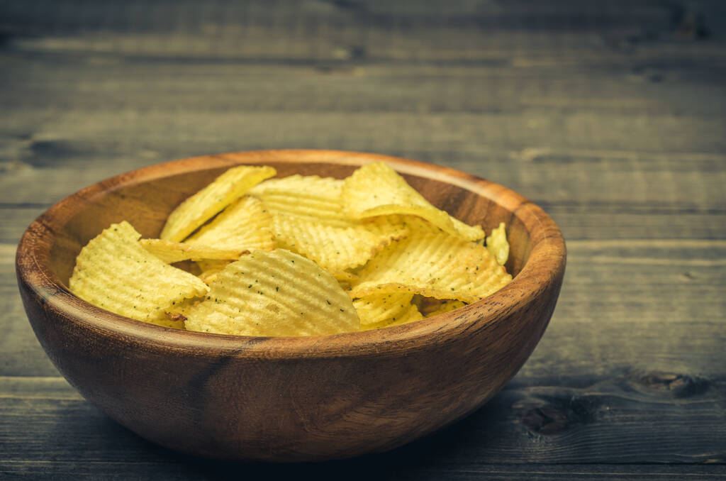 potato chips in a wooden bowl on a dark background/potato chips in a wooden bowl on a dark background. selective focus - Photo, Image