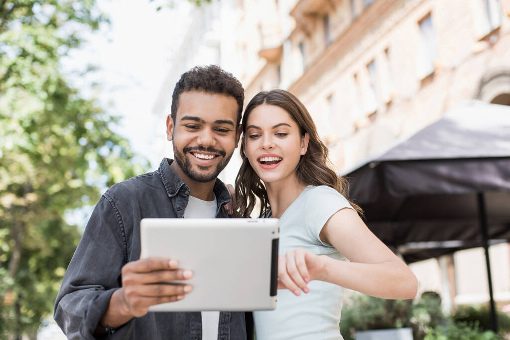 Krásný šťastný pár pomocí digitálního tabletu, Radostný úsměv žena a muž při pohledu na gadget ve městě ulici v létě, Láska, vztah, technologie, cestování a komunikace koncept - Fotografie, Obrázek