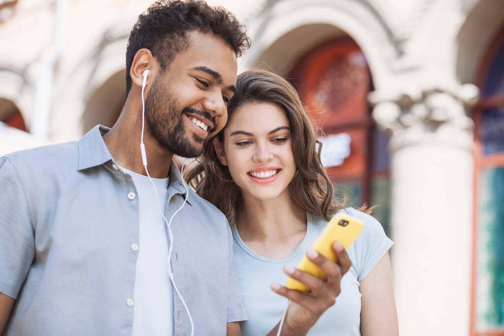 Gyönyörű boldog pár segítségével mobiltelefon egy városban, fiatal örömteli mosolygós nő és férfi nézi okostelefon, technológia, utazás, diákok koncepció - Fotó, kép