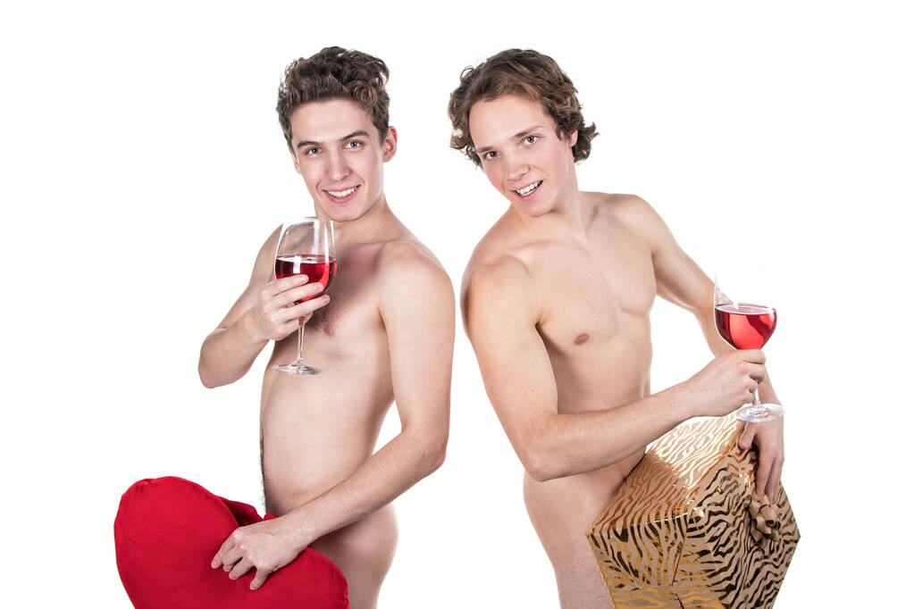 Dos chicos desnudos divertidos sosteniendo vasos con vino tinto y corazón aislado en blanco
 - Foto, imagen