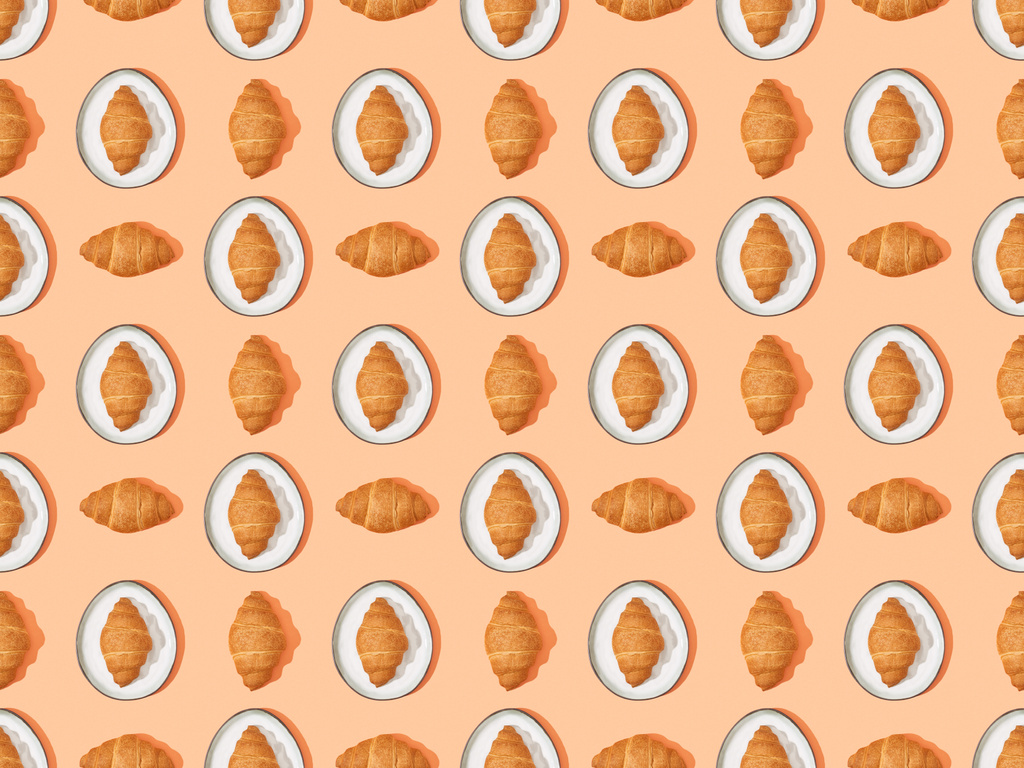 top view of fresh croissants on plates on orange, seamless background pattern - Photo, Image
