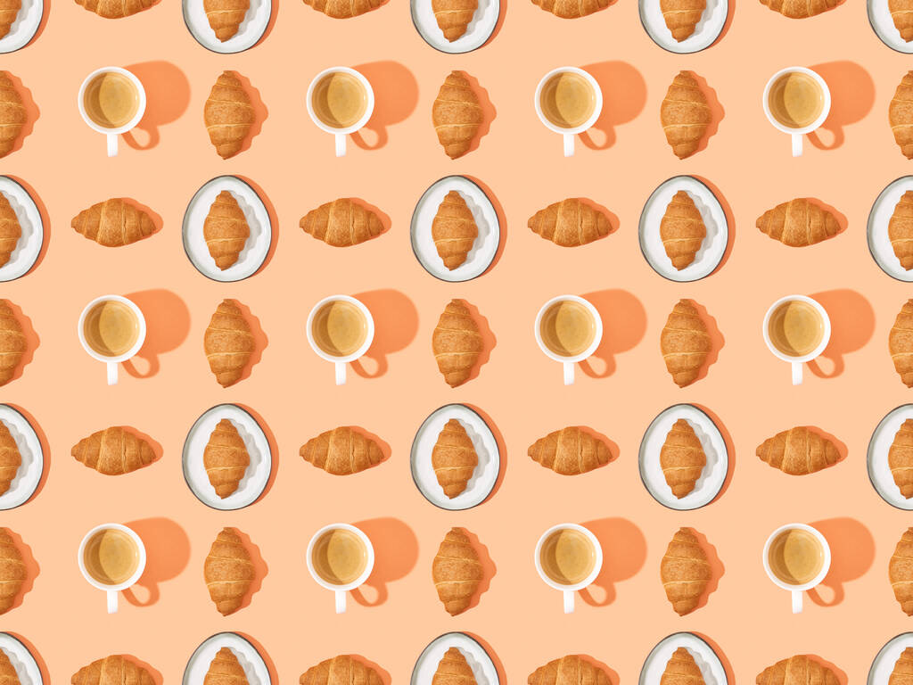 top view of fresh croissants on plates and coffee on orange, seamless background pattern - Photo, Image