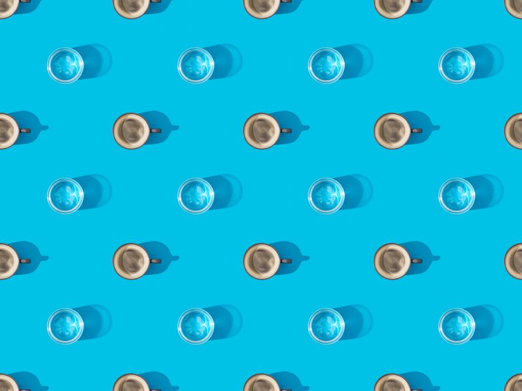 κορυφαία άποψη των φλιτζάνια του φρέσκου καφέ και ποτήρια του νερού σε μπλε, αδιάλειπτη μοτίβο φόντου - Φωτογραφία, εικόνα