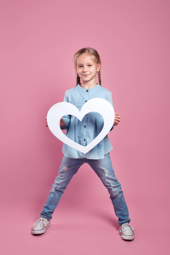 Meisje met papier wit hart op roze achtergrond - Foto, afbeelding