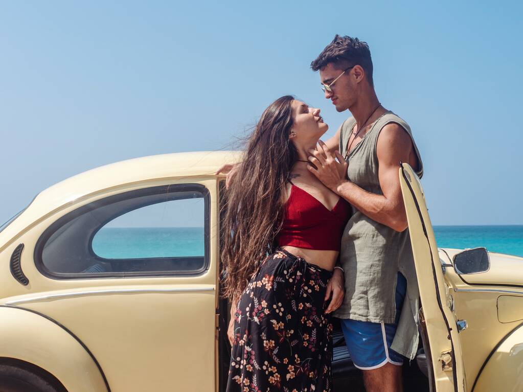 Um homem e uma jovem viajam num carro antigo. Palmas, praia oceânica
. - Foto, Imagem