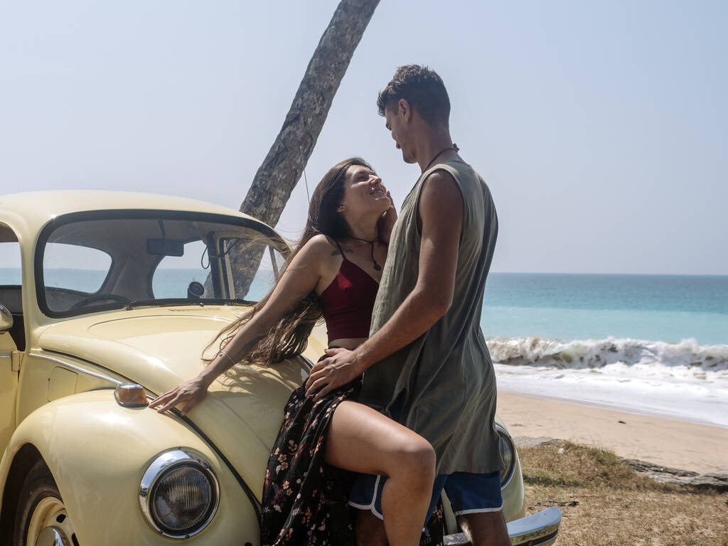 Bir erkek ve genç bir kadın klasik bir arabayla seyahat etmekten mutlu olurlar. Palmiyeler, okyanus plajı. Aşk hikayesi.. - Fotoğraf, Görsel