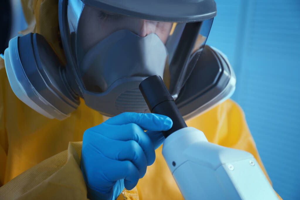 Wetenschapper in chemisch beschermend pak met behulp van microscoop in laboratorium, close-up. Virusonderzoek - Foto, afbeelding