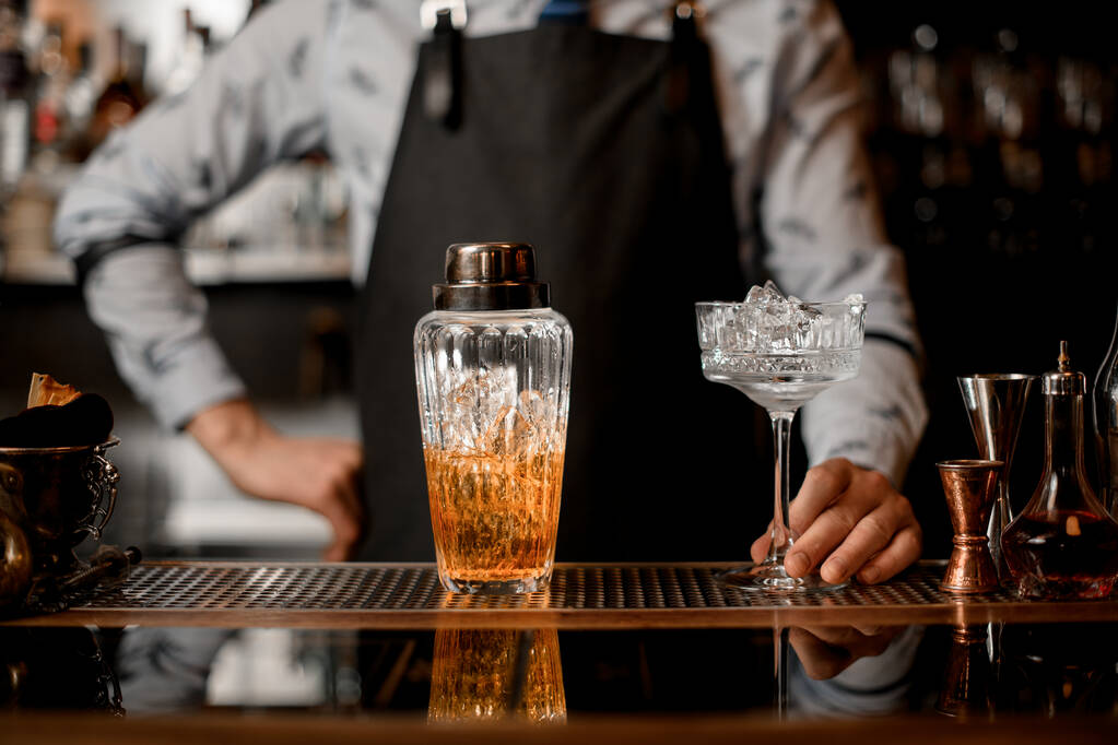 стеклянный шейкер с коктейльными столиками на барной стойке
. - Фото, изображение