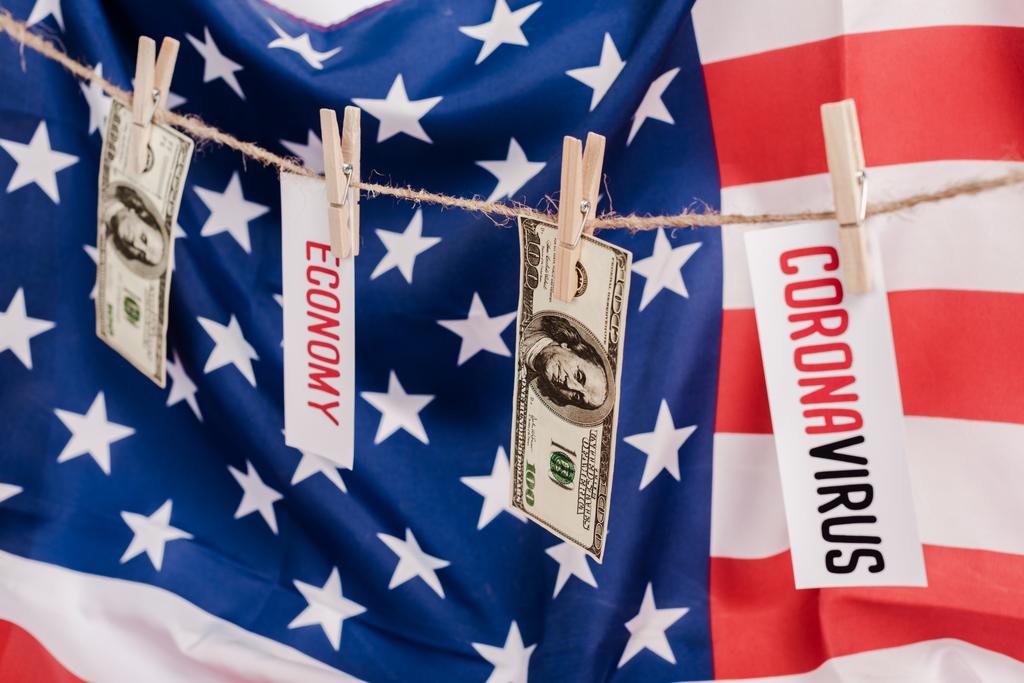 банкноти та карти доларів з економікою та коронавірусом, що висять на мотузці на американському фоні прапора
 - Фото, зображення