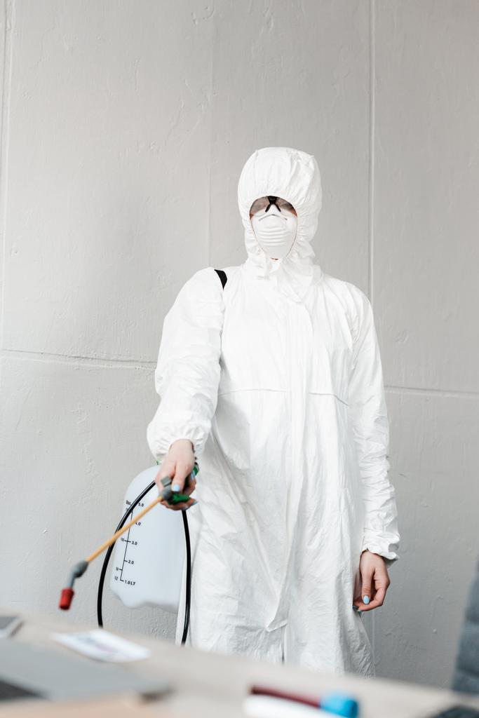 Beyaz tehlikeli madde giysisi, solunum cihazı ve gözlük takan, ofisteki işyerlerini dezenfekte eden, koronavirüs konsepti - Fotoğraf, Görsel