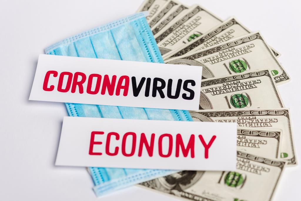 τραπεζογραμμάτια δολαρίων, ιατρική μάσκα και coronavirus και οικονομικές κάρτες σε λευκό φόντο - Φωτογραφία, εικόνα