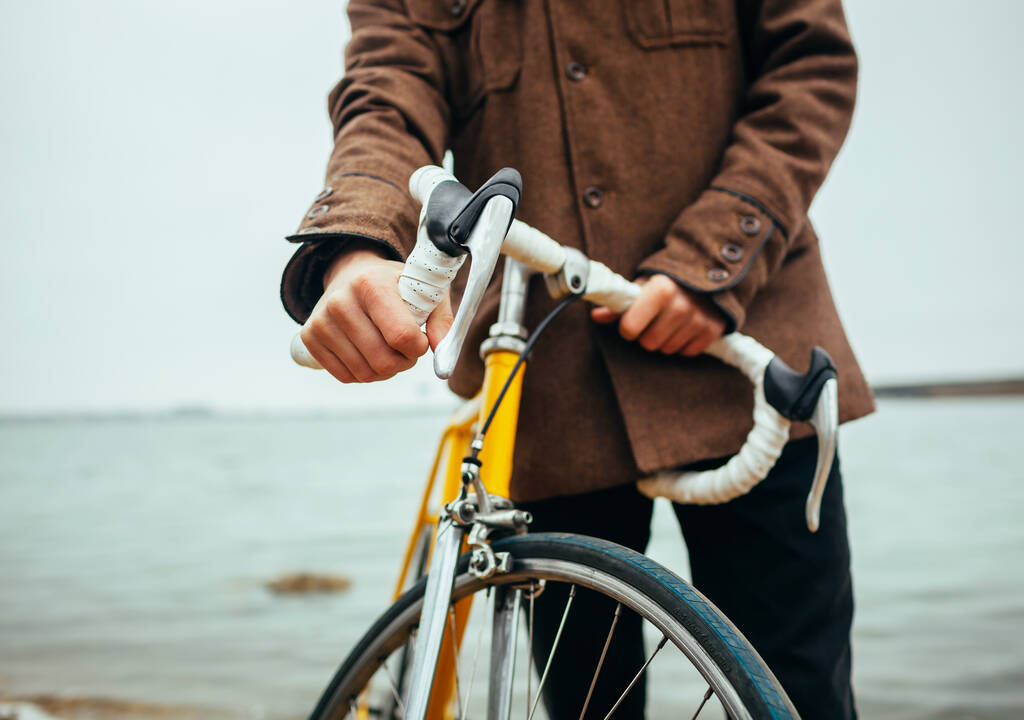 молодой человек с руками на руле велосипеда возле озера
 - Фото, изображение