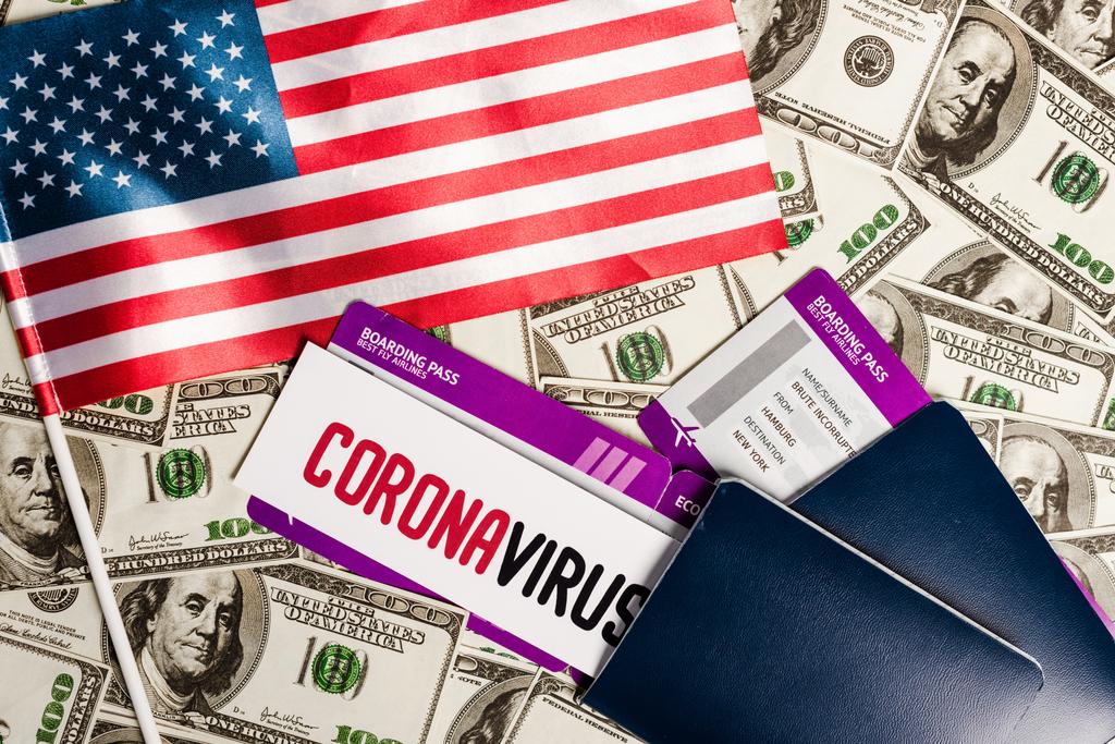 κορυφαία άποψη της αμερικανικής σημαίας και διαβατήρια με αεροπορικά εισιτήρια σε δολάρια χαρτονομίσματα, coronavirus έννοια της οικονομικής κρίσης - Φωτογραφία, εικόνα