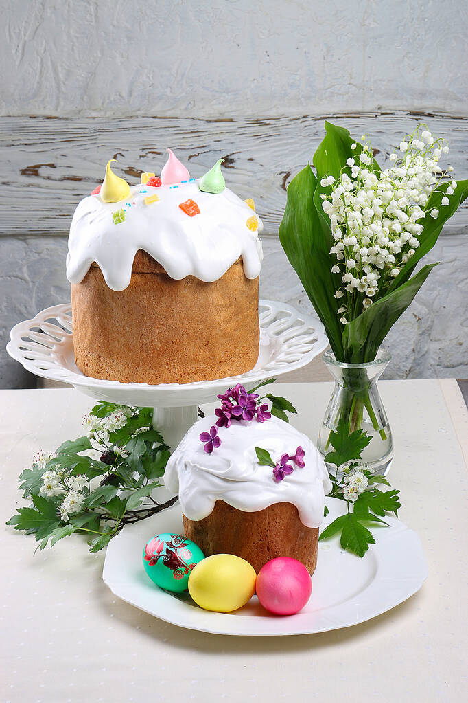 Wielkanocny tort Kulich. Tradycyjny chleb wielkanocny dekorowany bezy i trzciny cukrowej kształt jaj na talerzu na drewnianym tle stołu - Zdjęcie, obraz