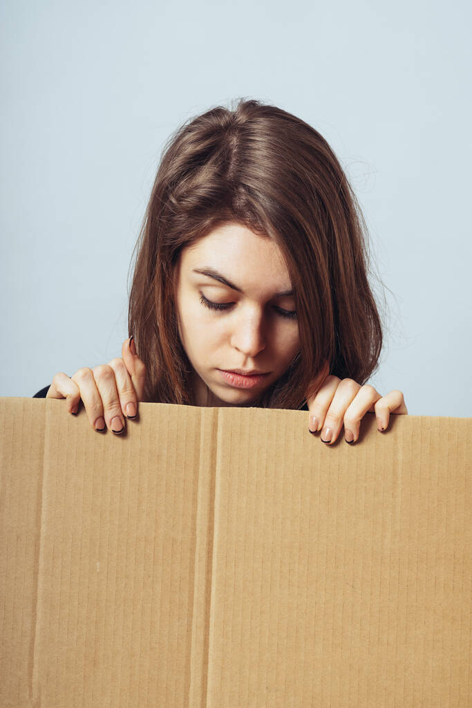 Девушка смотрит из-за картонной бумаги
 - Фото, изображение