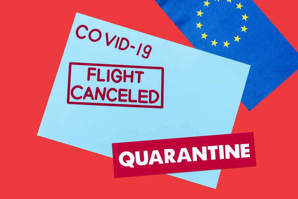 πάνω άποψη του μπλε φακέλου με covid-19, πτήση ακυρώθηκε και καραντίνα γράμματα κοντά σημαία της Ευρωπαϊκής Ένωσης που απομονώνονται σε κόκκινο  - Φωτογραφία, εικόνα