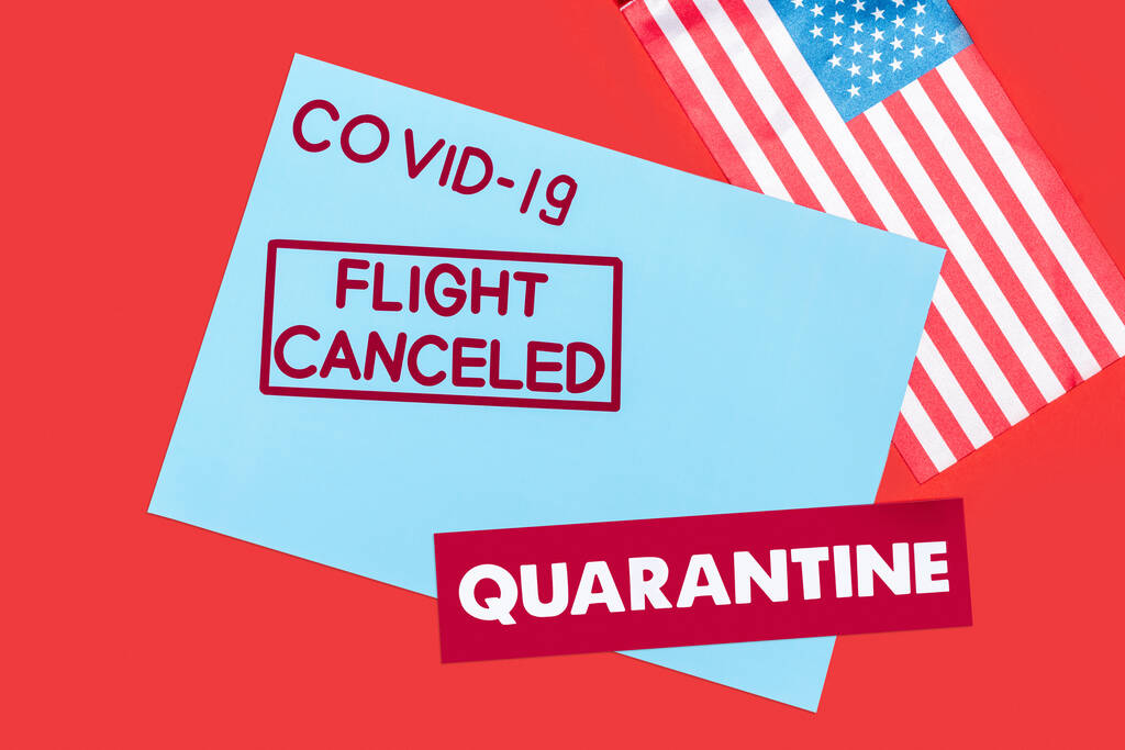 top view of blue envelope with covid-19, flight canceled and quarantine lettering near flag of america isolated on red  - Photo, Image