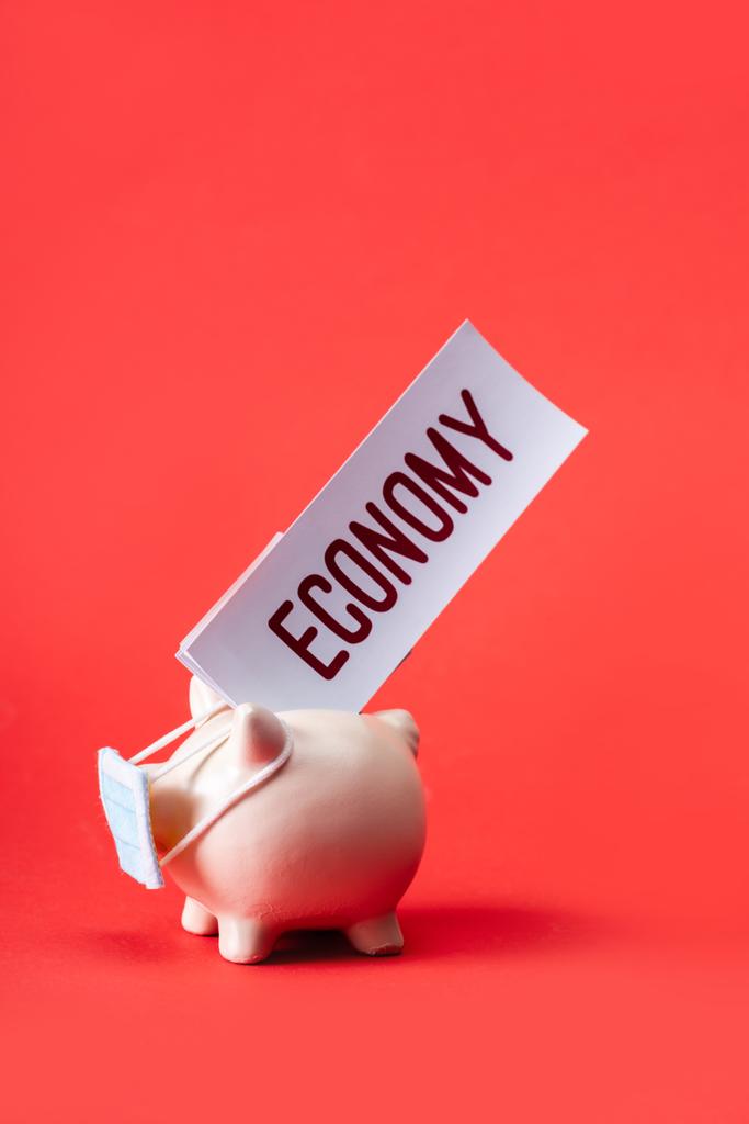 скарбничка в невеликій медичній масці з економічним випуском на червоному
  - Фото, зображення