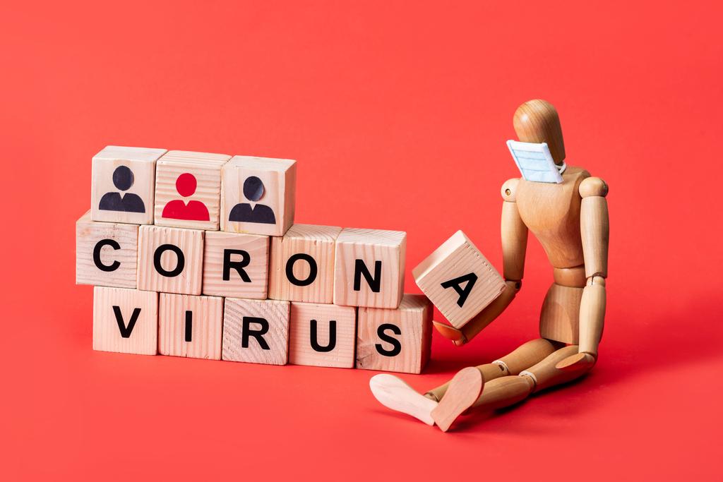 mannequin en bois en petit masque médical près de cubes avec lettrage coronavirus sur rouge
  - Photo, image