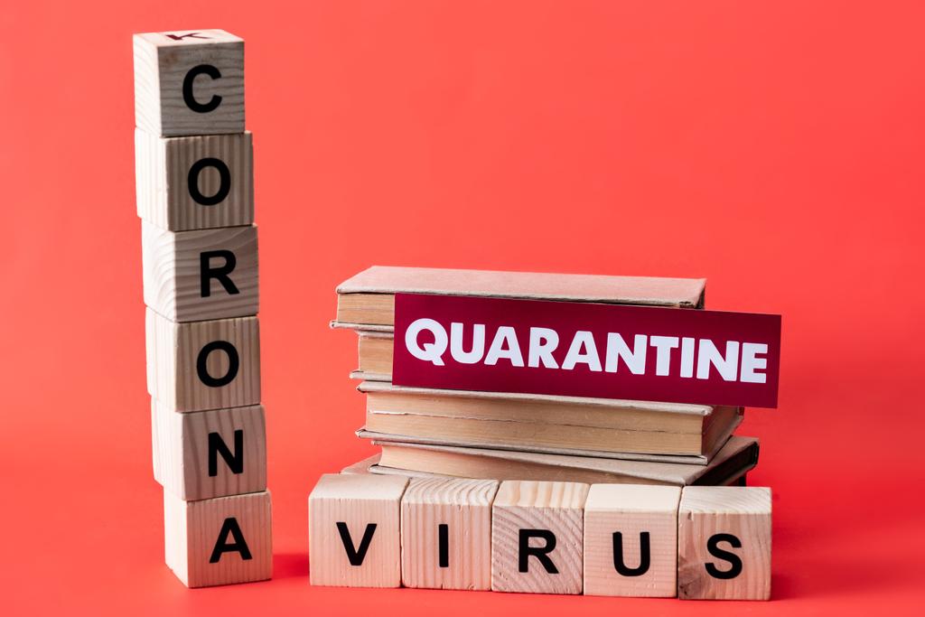 wooden cubes with coronavirus near books and quarantine lettering on red  - Photo, Image