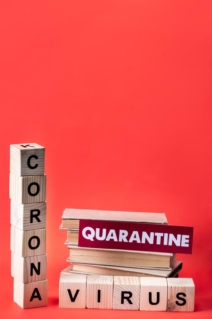 wooden cubes with coronavirus near books and quarantine lettering on red with copy space - Photo, Image