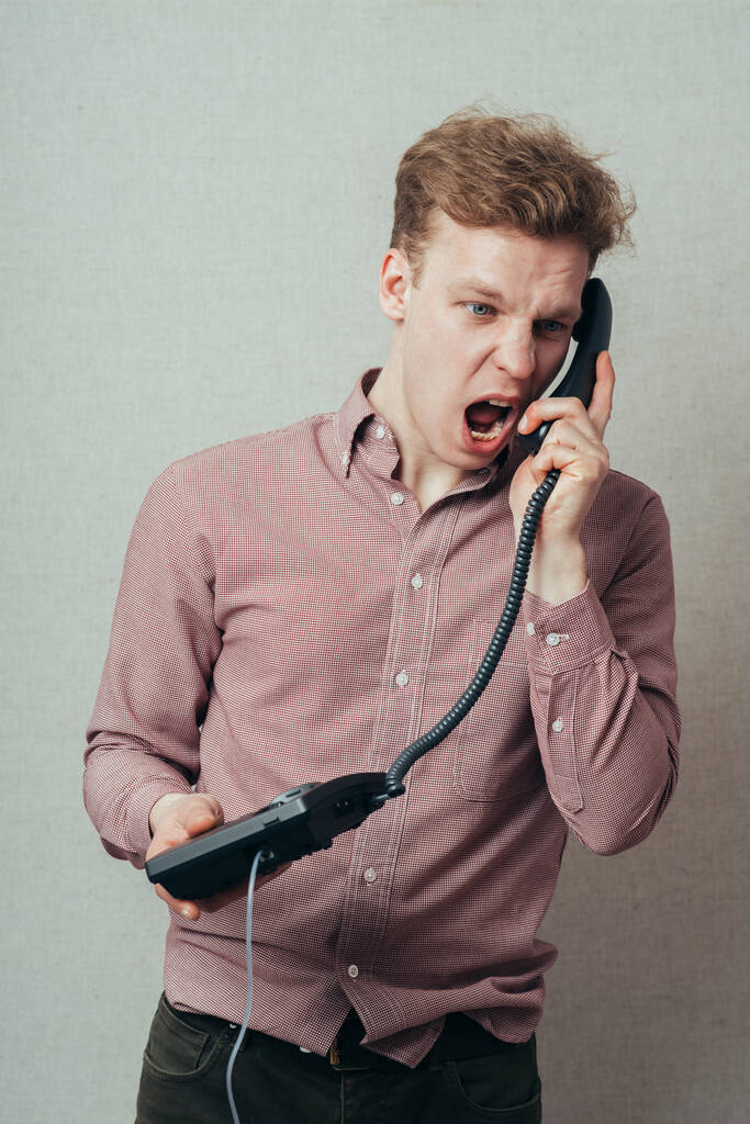 άντρας φωνάζει μιλώντας στο σταθερό τηλέφωνο - Φωτογραφία, εικόνα