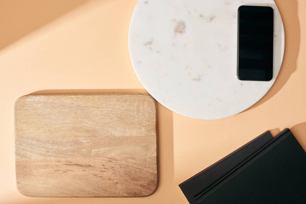 κάτοψη ξύλινων και μαρμάρινων σανίδων, smartphone και notebook σε μπεζ φόντο - Φωτογραφία, εικόνα