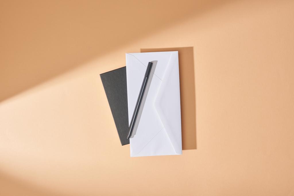 top view of envelope and pen on notebook on beige background - Photo, Image