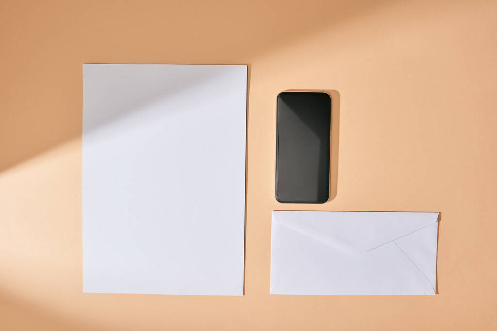 Üst sayfa kağıt, akıllı telefon ve bej arkaplan üzerindeki zarf görüntüsü - Fotoğraf, Görsel