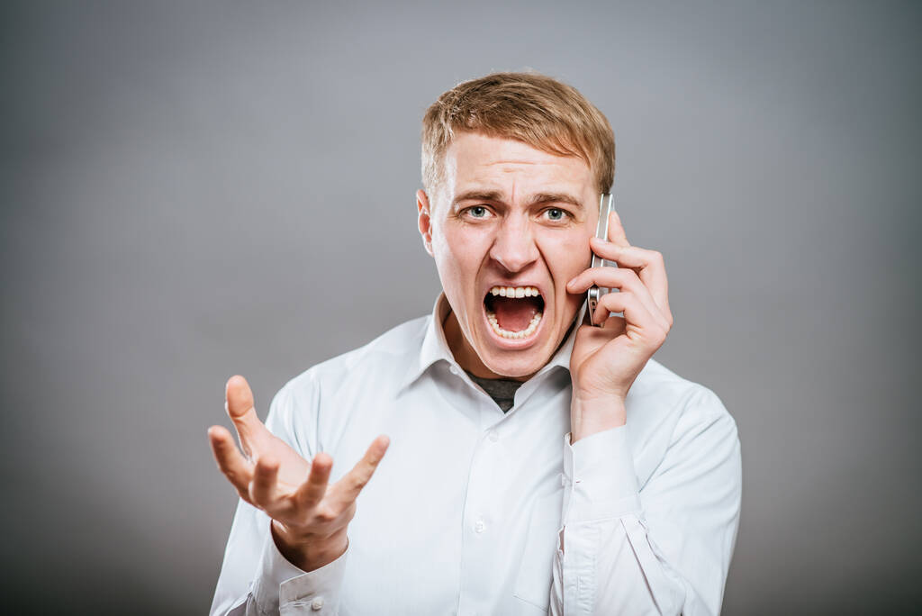 portrét rozzlobeného mladého muže křičícího pomocí mobilu  - Fotografie, Obrázek