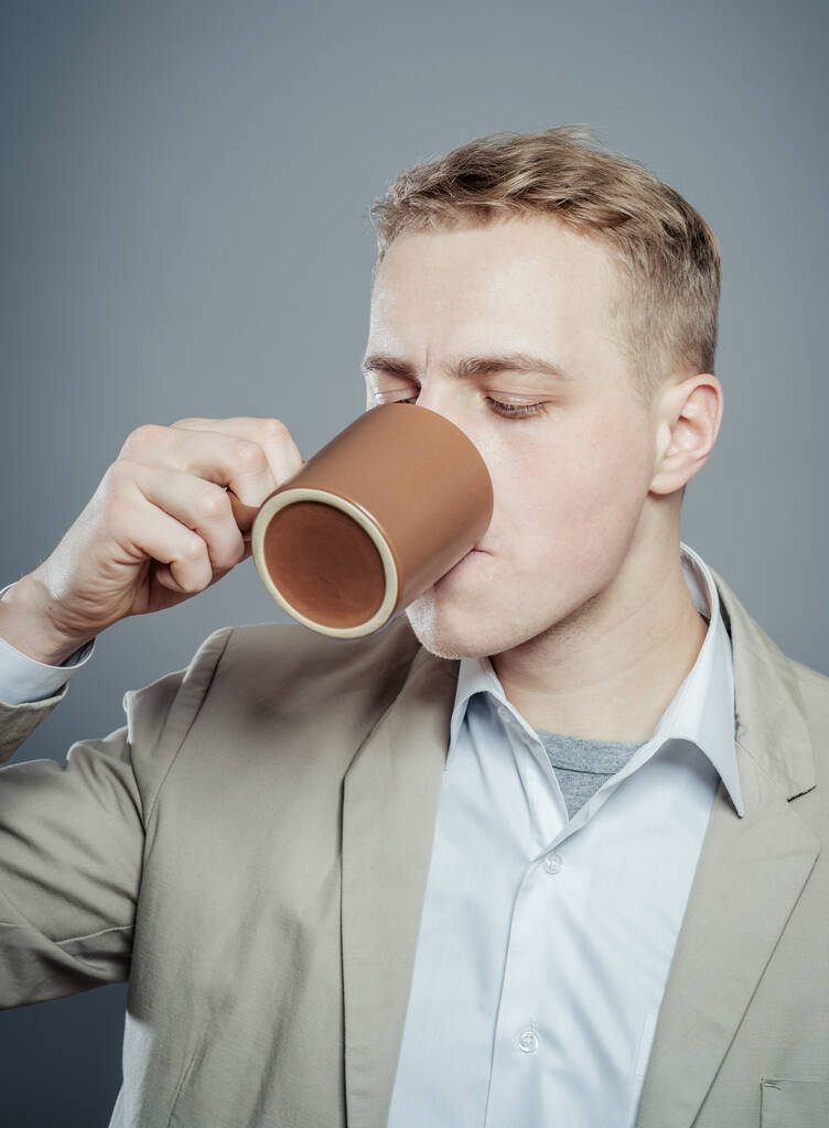 Πορτρέτο του όμορφος νεαρός άνδρας πίνουν ένα φλιτζάνι τσάι, καφέ, γάλα ή άλλα - Φωτογραφία, εικόνα