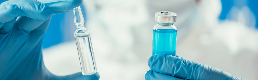 Teilansicht des Biochemikers mit Glasbehälter mit blauer Flüssigkeit und Ampulle  - Foto, Bild