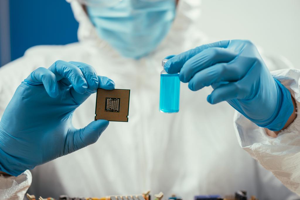 beschnitten Ingenieur hält Computer-Mikrochip und Glasbehälter mit blauer Flüssigkeit  - Foto, Bild