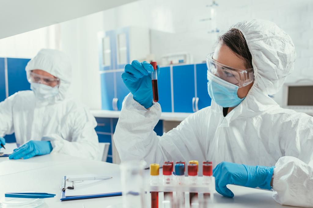 biokémikus kezében kémcső vérmintával közeli kolléga laboratóriumi - Fotó, kép
