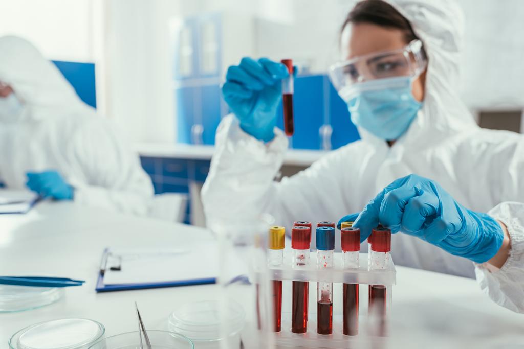 βιοχημικός εξεταστικός σωλήνας με δείγμα αίματος κοντά σε συνάδελφο στο εργαστήριο - Φωτογραφία, εικόνα